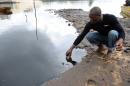 A man scoops spilled crude oil into a bottle from the waters of the Niger Delta swamps of Bodo, a village in Ogoniland, on June 24, 2010