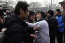 Dai Shuqin, whose sister was on board Malaysia Airlines Flight 370 that went missing on March 8, 2014, is stopped by policemen as she speaks to journalists near Yonghegong Lama Temple during a gathering of family members of the missing passengers, in Beijing Sunday, March 8, 2015. Families of the 239 people on board Malaysia Airlines Flight 370 on Sunday marked the anniversary of the plane's disappearance, vowing to never give up on the desperate search for wreckage and answers to the world's biggest aviation mystery. (AP Photo/Andy Wong)