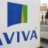 A man walks past an AVIVA logo outside the company's head office in the city of London