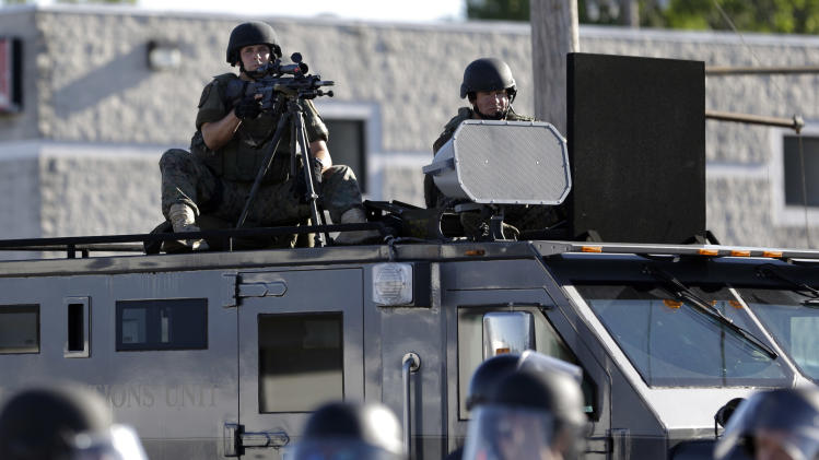 A police tactical team moves in to disperse a group of protesters on Wednesday, Aug. 13, 2014, in Ferguson, Mo. The protests were sparked after Michael Brown, an unarmed black man, was shot and killed by Darren Wilson, a white Ferguson police officer, on Aug. 9, 2014. (AP Photo/Jeff Roberson)