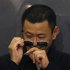 Director Wong removes confetti from sunglasses after beats drum with cast members at premiere of "The Grandmaster" in Hong Kong