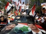 FILE - In this July 24, 2011 file photo, Syrian protesters carry pictures of Syrian President Bashar Assad and national flags, shout pro-government slogans in front of the Syrian embassy in Beirut. U.S. officials said Israel launched a rare airstrike inside Syria on Wednesday. The target was a convoy believed to be carrying anti-aircraft weapons bound for Hezbollah, the powerful Lebanese militant group allied with Syria and Iran. The Israeli airstrike comes at a particularly sensitive and vulnerable time for Hezbollah in Lebanon. Despite its formidable weapons arsenal and political clout in the country, the group's credibility and maneuvering space has been significantly reduced in the past few years, largely because of the war in neighboring Syria but also because of unprecedented challenges at home. (AP Photo/Bilal Hussein, File)