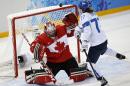 Goalkeeper Shannon Szabados of Canada blocks a shot at the goal under pressure from Susanna Tapani of Finland during the third period of the 2014 Winter Olympics women's ice hockey game at Shayba Arena, Monday, Feb. 10, 2014, in Sochi, Russia. Canada defeated Finland 3-0. (AP Photo/Petr David Josek)