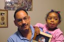 In this Sept. 20, 2012 photo, Robert Garcia holds his daughter Amara Garcia, 3, in their apartment in the Bronx borough of New York, as she displays a photograph of her grandfather Felix Garcia and his late wife. Felix Garcia is enrolled in an overnight program for dementia victims with sleep problems at the Hebrew Home at Riverdale, also in the Bronx. (AP Photo/Jim Fitzgerald)