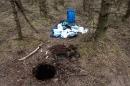 An undated handout photograph released by the Police Service of Northern Ireland, and made available in London on May 17, 2016, shows a barrell containing munitions near to the hole it was discovered in, in Capanagh Forest in Larne, Northern Ireland