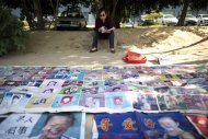 Ye Jinxiu, 59, sits before pictures of missing children on the streets of Fuzhou on China's east coast Fujian province, on October 23, 2013