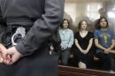 Members of the female punk band "Pussy Riot" sit in a glass-walled cage during a court hearing in Moscow