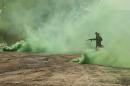 In this Saturday, Aug. 13, 2016 photo, a soldier from the 1st Battalion of the Iraqi Special Operations Forces in the role of an Islamic State militant runs through green smoke during a training exercise to prepare for the operation to re-take Mosul from IS, in Baghdad, Iraq. Iraq's leaders have repeatedly promised that Mosul — which has been in the hands of IS militants for more than two years now — will be retaken this year. (AP Photo/Maya Alleruzzo)