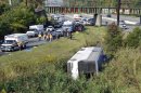 Rescue workers and passengers stand by after a bus overturned in a ditch at an exit ramp off Route 80 in Wayne, N.J. Saturday, Oct. 6, 2012. The chartered tour bus from Toronto carrying about 60 people overturned on an interstate exit ramp. Three people have been taken to hospital with non-life-threatening injuries. (AP Photo/Bill Kostroun)