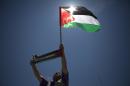 A Palestinian protester raises up a flag and a banner reading "Palestine" during a rally mon May 13, 2014 in Gaza city