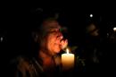 A woman holding a candle and a rose cries outside the house of former South African president Nelson Mandela following his death in Johannesburg on December 5, 2013