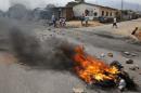 Residents move past a burning barricade on a rock strewn street in Bujumbura's Niyakabiga district on Presidential election day in Burundi