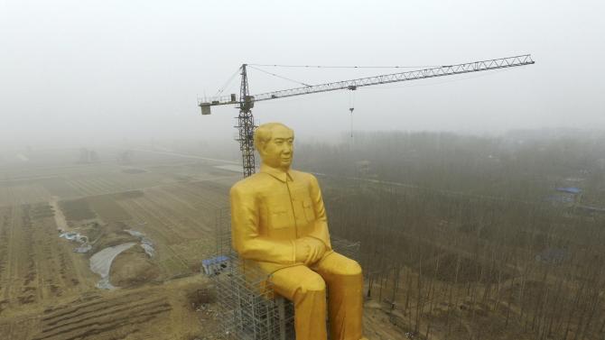 A crane is seen next to a giant statue of Chinese late chairman Mao Zedong under construction near crop fields in a village of Tongxu county, China