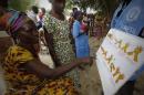 Women look at a poster on Ebola prevention at Toulepleu