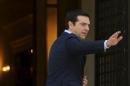 Greek Prime Minister Alexis Tsipras waves to journalists as he arrives at his office at the Maximos Mansion after a swearing in ceremony of members of his government at the Presidential Palace in Athens