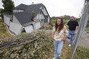 In this photo taken Monday, May 6, 2013 Robin and Scott Spivey walk past the wreckage of their Tudor-style dream home they had to abandon when the ground gave way causing it to drop 10 feet below the street in Lakeport, Calif. Officials believe that water that has bubbled to the surface is playing a role, in the collapse of the hillside subdivision that has forced the evacuation of 10 homes and the notice of imminent evacuation of another 10 in this upscale subdivision.(AP Photo/Rich Pedroncelli)