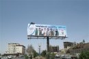 Workers put up a billboard urging citizens to cooperate with security authorities in Sanaa