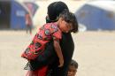 An Iraqi woman displaced from the city of Fallujah carries a child at a newly opened camp where hundreds of Iraqis are taking shelter in Amriyat al-Fallujah on June 27, 2016