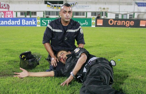 A police officer lies on the pitch after he was injured in clashes with soccer fans during the African Champions League match between Etoile Sportive du Sahel and Esperance Sportive de Tunis at Sousse olympic stadium