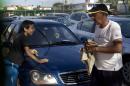 A car dealership worker, right, and a boy clean a used Chinese Geely for sale at a government-run dealership in Havana, Cuba, Thursday, Jan. 2, 2014. This car once was for sale for $5,000 dollars, but the price has risen to as much as $30,000, after a new law took effect eliminating a special permit requirement that has greatly restricted vehicle ownership in the country. (AP Photo/Ramon Espinosa)