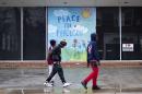 Youths walk past a mural depicting peace in Ferguson on a vacant building up the street from the city's police department, Sunday, Nov. 23, 2014, in Ferguson, Mo. Ferguson and the St. Louis region are on edge in anticipation of the announcement by a grand jury whether to criminally charge Officer Darren Wilson in the killing of 18-year-old Michael Brown. (AP Photo/David Goldman)