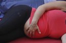 A pregnant woman touches her stomach as people practice yoga on the morning of the summer solstice in New York's Times Square