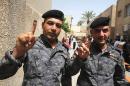 Iraqi police officers show their inked fingers at a polling center in Baghdad, Iraq, Monday, April 28, 2014. Iraqi officials say suicide bombers have targeted polling centers as soldiers and security forces cast ballots ahead of parliamentary elections. (AP Photo/ Karim Kadim)