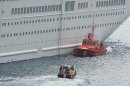 An orange rescue boat docks by a capsized lifeboat, obscured behind, from the British-operated cruise ship Thomson Majesty in Santa Cruz port of the Canary Island of La Palma, Spain, Sunday Feb. 10, 2013. A lifeboat from the Thomson Majesty fell into the sea at port in Spain's Canary Islands, killing five people and injuring three others Sunday, officials said. Rescue personnel were called to the dockside after a lifeboat with occupants had fallen overboard from a cruise ship. Spanish national broadcaster RTVE said an emergency training drill was taking place at the time of the accident. (AP Photo/Manuel Gonzalez)