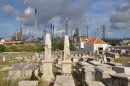 In this Nov. 12, 2012 photo, a portion of the Beth Haim cemetery, backdropped by the Isla oil refinery, is seen in Blenheim, on the outskirts of Willemstad, Curacao. Beth Haim, believed to be one of the oldest Jewish cemeteries in the Western Hemisphere, established in the 1950s and considered an important landmark on an island where the historic downtown has been designated a UNESCO World Heritage Site, is slowly fading in the Caribbean sun. Headstones are pockmarked with their inscriptions faded, stone slabs that have covered tombs in some cases for hundreds of years are crumbling into the soil, marble that was once white is now grey, likely from the acrid smoke that spews from the oil refinery that looms nearby. (AP Photo/Karen Attiah)
