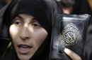 An Iranian protester chants slogans as she holds a copy of the Quran, Muslims' holy book, in front of the French Embassy in Tehran, Iran, Thursday, Sept. 20, 2012, during a protest the publication of caricatures of Islam's Prophet Muhammad by a French satirical weekly. Dozens of Iranian students and clerics gathered outside the embassy and chanted "Death to France" and "Down with the U.S." and burned the representation of the U.S. and Israeli flags Thursday. (AP Photo/Vahid Salemi)