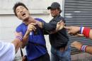 Anti-government protesters attack a voter near a polling station in Bangkok