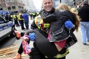In this Monday, April 15, 2013 photo, Boston Firefighter James Plourde carries an injured girl away from the scene after a bombing near the finish line of the Boston Marathon in Boston. The FBI's investigation into the bombings at the Boston Marathon was in full swing Tuesday, with authorities serving a warrant on a suburban Boston home and appealing for any private video, audio and still images of the blasts that killed at least three and wounded more than 170. (AP Photo/MetroWest Daily News, Ken McGagh) MANDATORY CREDIT