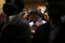 Immigrants stand for the invocation during a naturalization ceremony to become new U.S. citizens at Boston College in Chestnut Hill