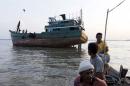 Acehnese fishermen pass near an abandoned boat which carried Rohingya and Bangladeshi migrants from Thailand, found off the coast near the city of Kuta Binje