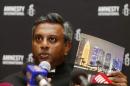 Amnesty International Secretary General Salil Shetty holds up a report during a news conference in Doha