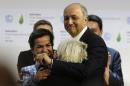 French Foreign Minister Laurent Fabius (R) hugs French Ambassador for COP21 Laurence Tubiana, as Executive Secretary of the UNFCCC Christiana Figueres (L) looks on, in Le Bourget on December 12, 2015