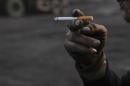A worker smokes a cigarette during a break at a coal freight yard in Hefei, Anhui province, January 13, 2013. REUTERS/Stringer/Files