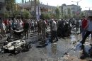 People stand at the site of an explosion in Ekrema neighbourhood in Homs city