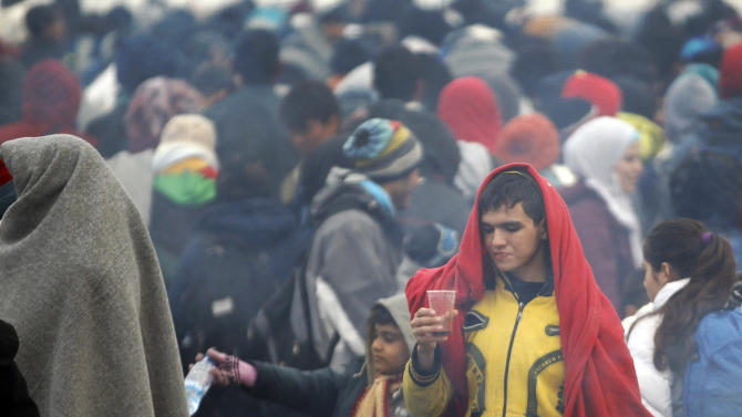 A young man hholds a cup in a crowd of hundreds of migrants waiting to enter a camp in Spielfeld, Austria, Monday, Oct. 26, 2015. Thousands of people trying to reach central and northern Europe via the Balkans often have to wait for days in the cold rain and mud at the borders. (AP Photo/Petr David Josek)