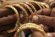 A woman holds gold bangles at a jewellery shop in Kolkata October 14, 2009. REUTERS/Jayanta Shaw/Files
