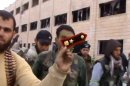In this Sunday March 3, 2013 image taken from video obtained from the Shaam News Network, which has been authenticated based on its contents and other AP reporting, a Syrian rebel fighters displays an epaulette from a government soldier during a tour of the police academy complex in Khan al-Asal, in the province of Aleppo, Syria. The Britain-based Syrian Observatory for Human Rights said the rebels seized the police academy in Khan al-Asal after entering the sprawling government complex with captured tanks. The Observatory said the battle left at least 120 soldiers and 80 rebels dead. (AP Photo/Shaam News Network via AP video)