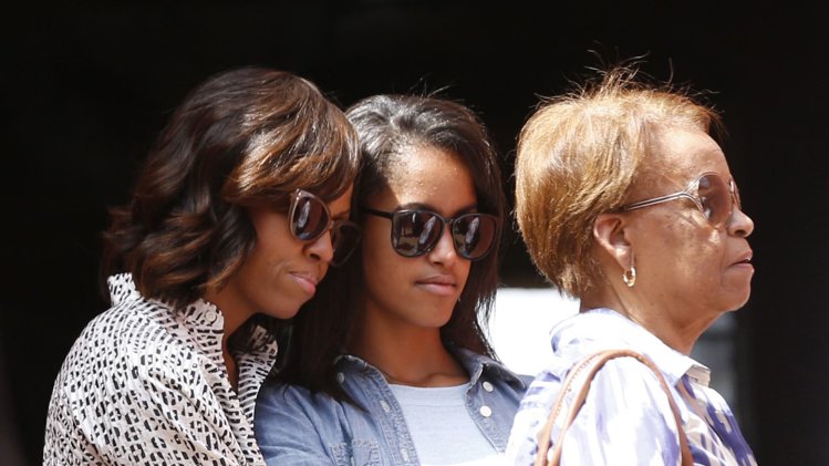 U.S. first lady Michelle Obama hugs her daughter Malia alongside Marian Robinson, Michelle Obama's mother, as they visit the Maison Des Ecslaves on Goree Island