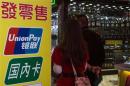 Chinese visitors walk past a sign for China UnionPay outside a pawnshop in Macau