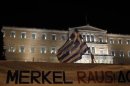 Protesters hold banner in front of parliament during rally against the upcoming visit by German Chancellor Merkel in Athens
