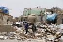 People walk at the site of a Saudi-led air strike that hit a residential area last month near Sanaa airport
