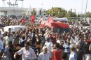 People walk beside the ambulance carrying the body of assassinated Tunisian opposition politician Brahmi in Tunis