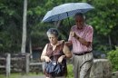 A couple uses an umbrella as it rains Ponce, Puerto Rico, Wednesday, July 31, 2013. Puerto Ricans are used to wet tropical weather, but the past few weeks have been the wettest ever recorded in the U.S. island territory. (AP Photo/Ricardo Arduengo)