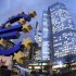 The Euro sculpture stands in front of the European Central Bank, right,  in Frankfurt, Germany, on Friday, Dec.16, 2011. Poster underneath the Euro sign reads: Let's talk about Future. (AP Photo/Michael Probst)