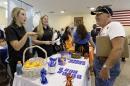 In this photo taken Wednesday, July 16, 2014, job seeker U.S. Army veteran John Godman, right, talks to recruiters Nicole Rushton, left, and Megan Hogan, center, at a Hiring Fair For Veterans in Fort Lauderdale, Fla. The Labor Department releases weekly jobless claims on Thursday, July 23, 2014. (AP Photo/Alan Diaz)