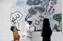 Pro-Houthi activists finish painting graffiti depicting Saudi-led air strikes on the wall of the Saudi embassy in Sanaa